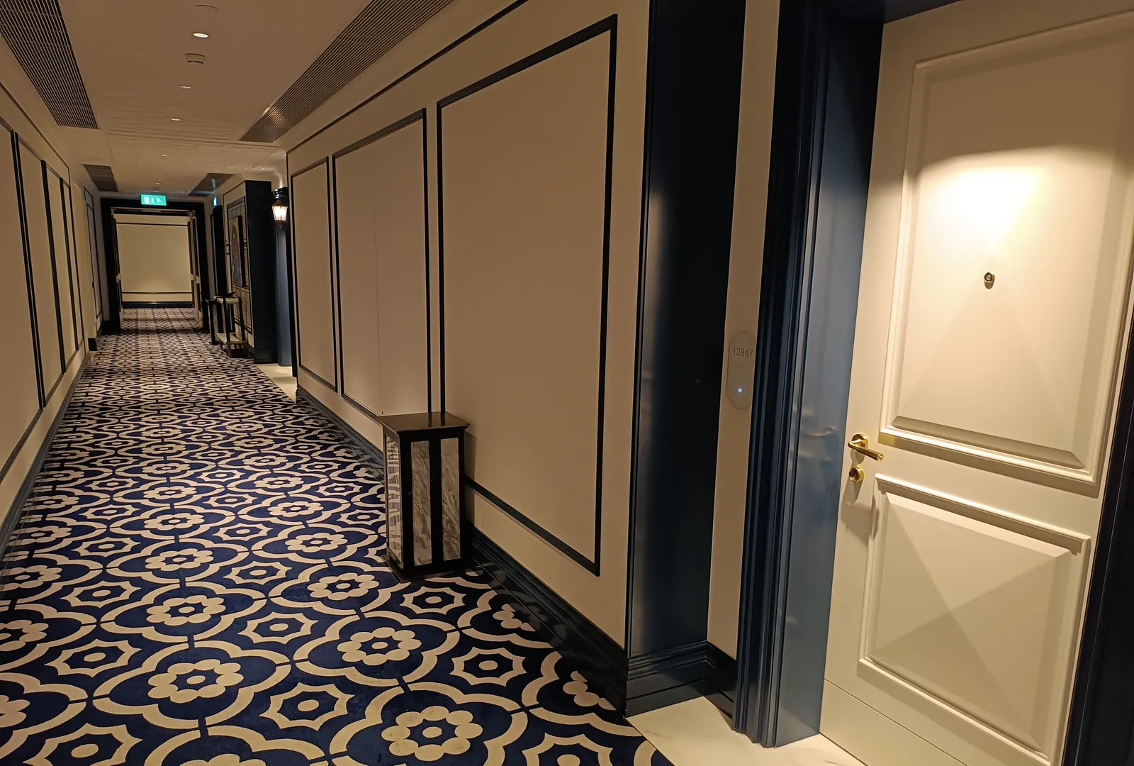 Heller Hotelflur mit gemustertem Teppich und weißen Zimmertüren