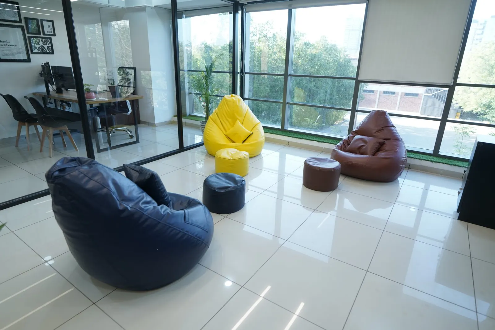 Heller, aufgeräumter Büro-Loungebereich mit Sitzsäcken, Glaswänden und glänzendem Fliesenboden